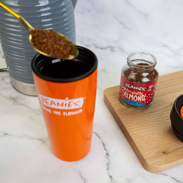 Decaf Amaretto Almond Jar alongside an orange travel cup.